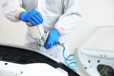 Photo of Worker painting car in body shop, closeup