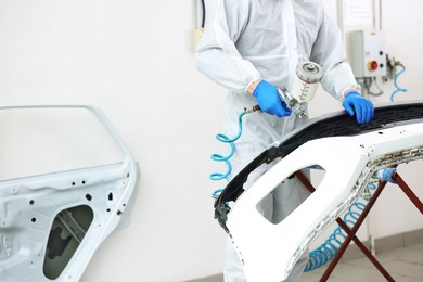 Photo of Worker painting car in body shop, closeup