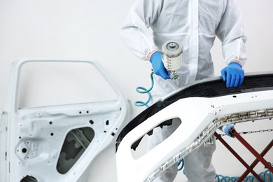 Photo of Worker painting car in body shop, closeup