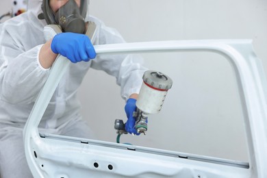 Photo of Worker painting car door in body shop, closeup