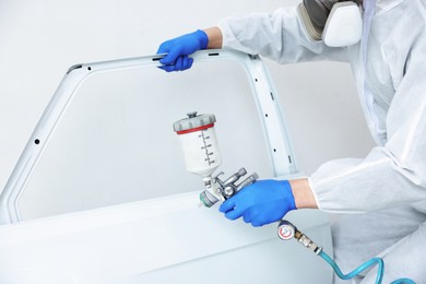 Photo of Worker painting car door in body shop, closeup