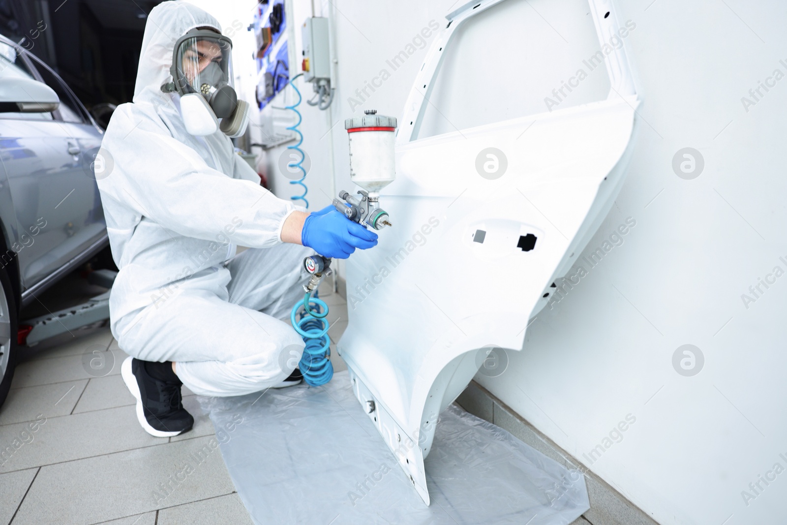 Photo of Worker painting car door in body shop