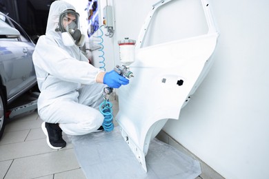 Photo of Worker painting car door in body shop