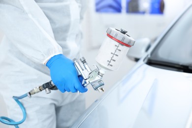 Photo of Worker painting car in body shop, closeup