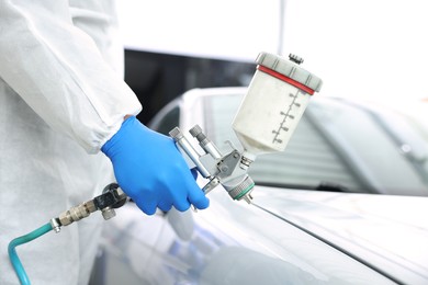 Photo of Worker painting car in body shop, closeup