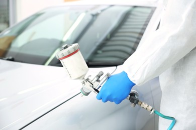 Photo of Worker painting car in body shop, closeup