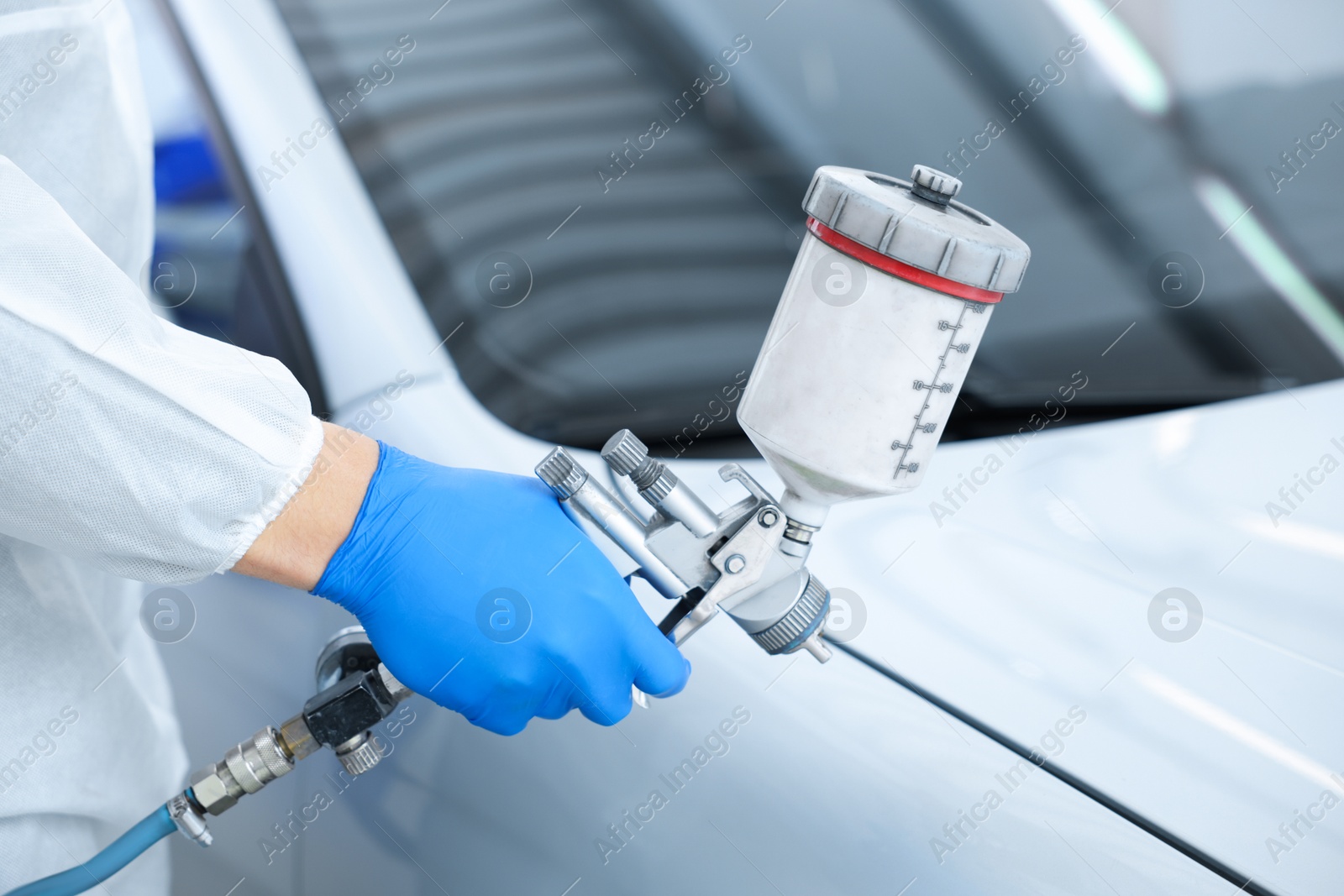 Worker painting car in body shop, closeup Photo of Worker painting car in body shop, closeup