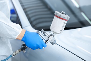Photo of Worker painting car in body shop, closeup