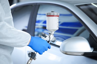 Photo of Worker painting car in body shop, closeup