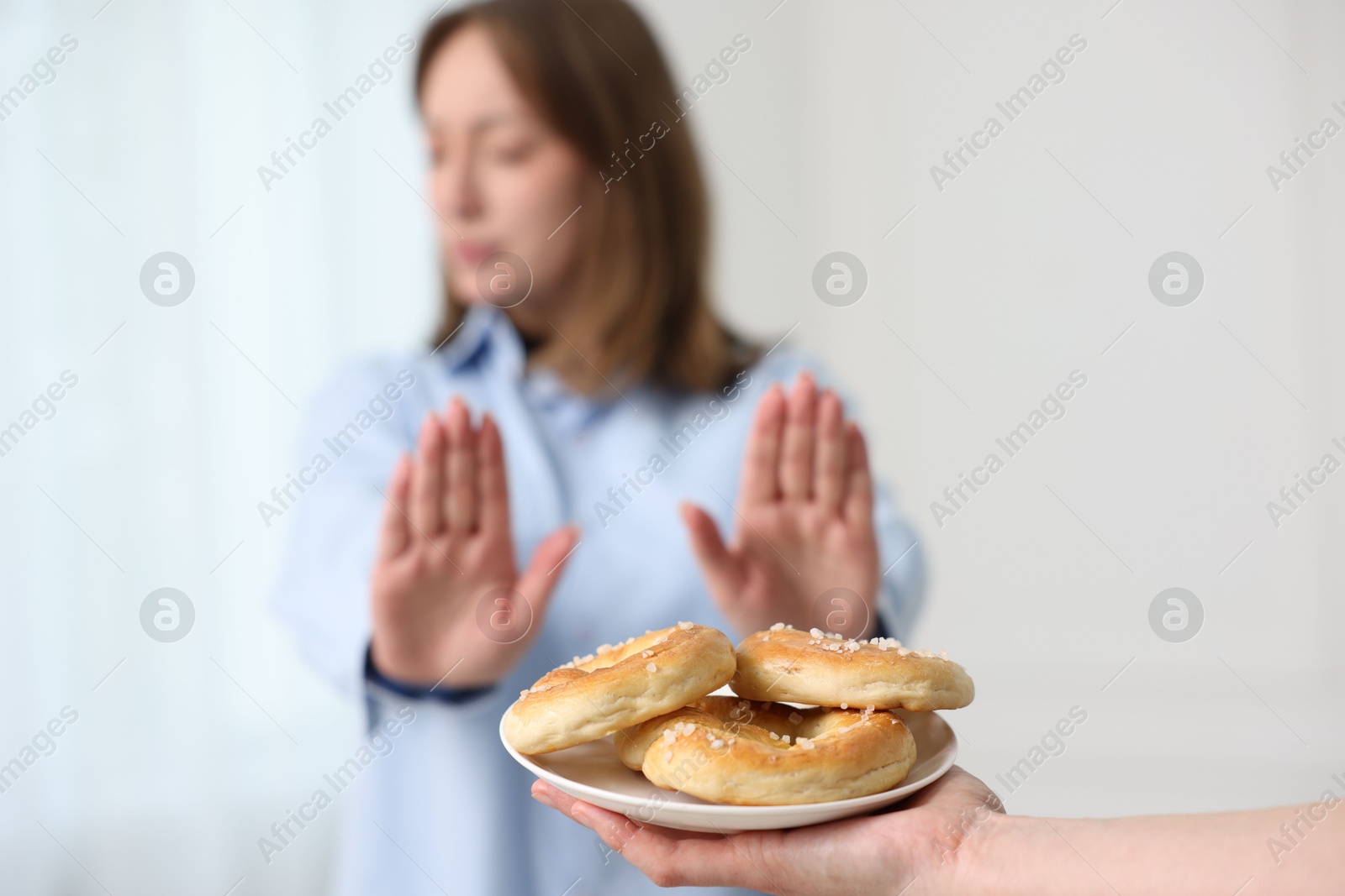 Photo of Gluten free diet. Woman refusing from pretzels indoors, selective focus