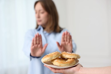 Photo of Gluten free diet. Woman refusing from pretzels indoors, selective focus