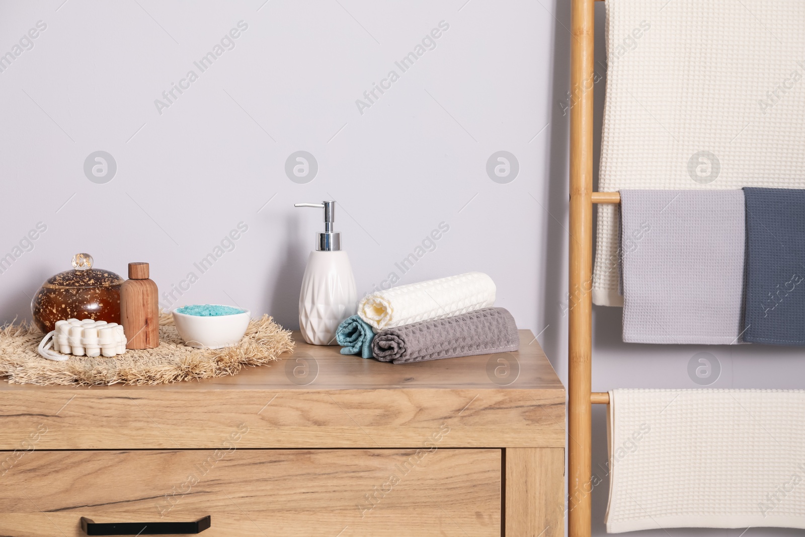 Clean waffle towels and other bath products on wooden dresser Photo of Clean waffle towels and other bath products on wooden dresser