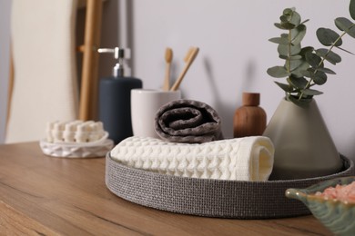 Photo of Clean waffle towels and other bath products on wooden dresser, closeup