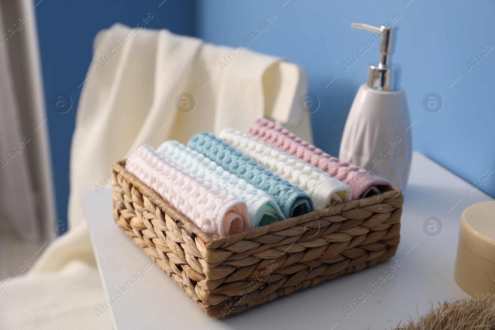Clean waffle towels in wicker basket on white dresser in bathroom, closeup Photo of Clean waffle towels in wicker basket on white dresser in bathroom, closeup
