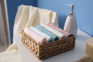 Photo of Clean waffle towels in wicker basket on white dresser in bathroom, closeup