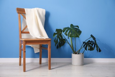 Photo of Clean waffle towel on chair and houseplant near blue wall