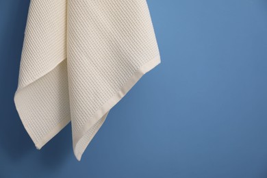 Photo of Clean waffle towel hanging on blue wall, closeup. Space for text