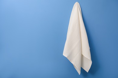 Photo of Clean waffle towel hanging on blue wall, space for text