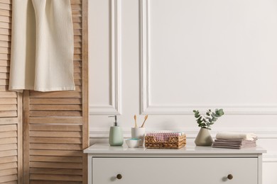 Photo of Clean waffle towels and other bath products on white dresser in bathroom