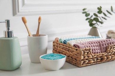 Photo of Clean waffle towels and other bath products on white dresser in bathroom, closeup