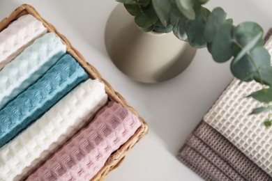 Photo of Clean waffle towels and vase with branches on white table in bathroom, flat lay