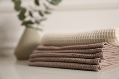 Photo of Clean waffle towels on white table in bathroom, closeup