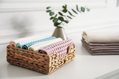 Photo of Clean waffle towels and vase with branches on white dresser in bathroom, closeup