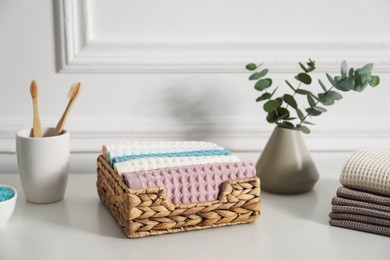 Photo of Clean waffle towels and other bath products on white dresser in bathroom