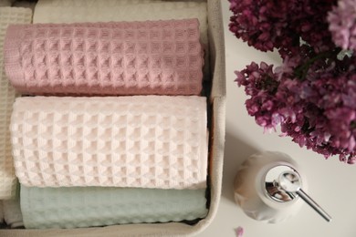 Photo of Clean waffle towels and vase of lilac flowers on white table, flat lay