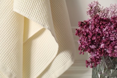 Photo of Clean waffle towels and vase of lilac flowers in bathroom, closeup