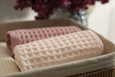 Photo of Clean waffle towels in basket and vase of lilac flowers, closeup