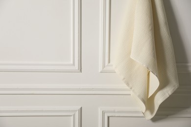 Photo of Clean waffle towel hanging on white wall, closeup. Space for text