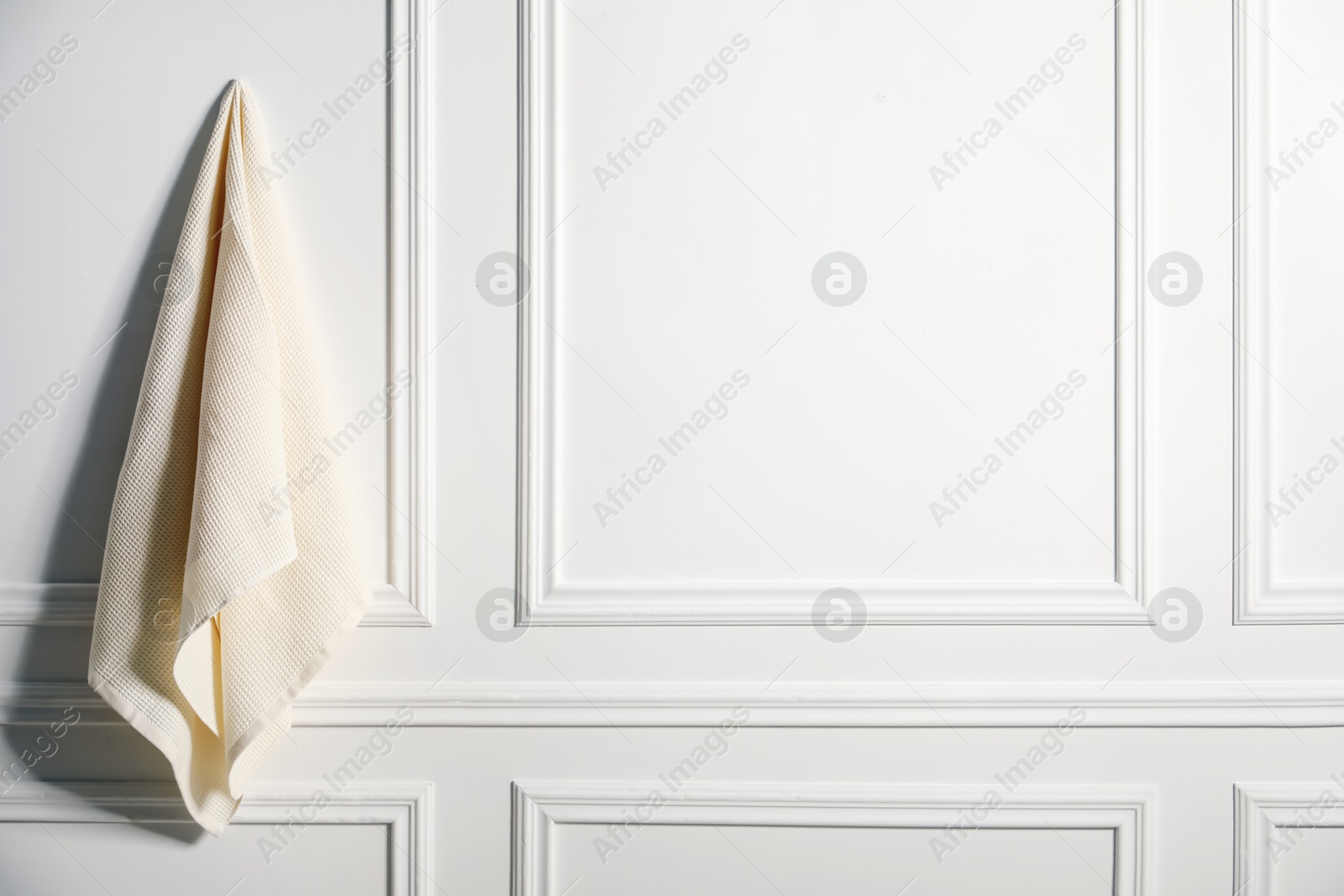 Clean waffle towel hanging on white wall, space for text Photo of Clean waffle towel hanging on white wall, space for text