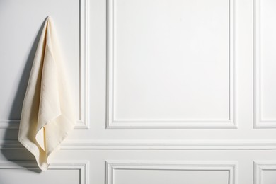 Photo of Clean waffle towel hanging on white wall, space for text