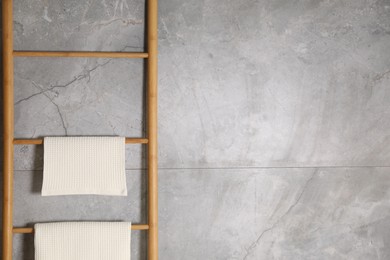 Photo of Clean waffle towels on wooden rack near grey wall. Space for text