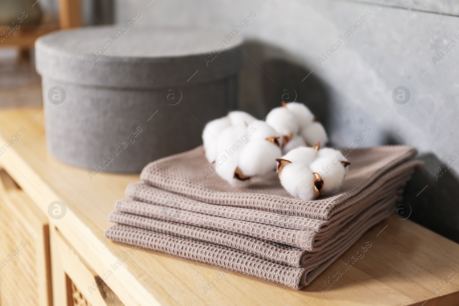 Clean waffle towels and cotton flowers on wooden dresser in bathroom, closeup Photo of Clean waffle towels and cotton flowers on wooden dresser in bathroom, closeup
