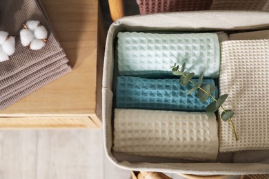 Photo of Clean waffle towels on wooden dresser and chair in bathroom, top view
