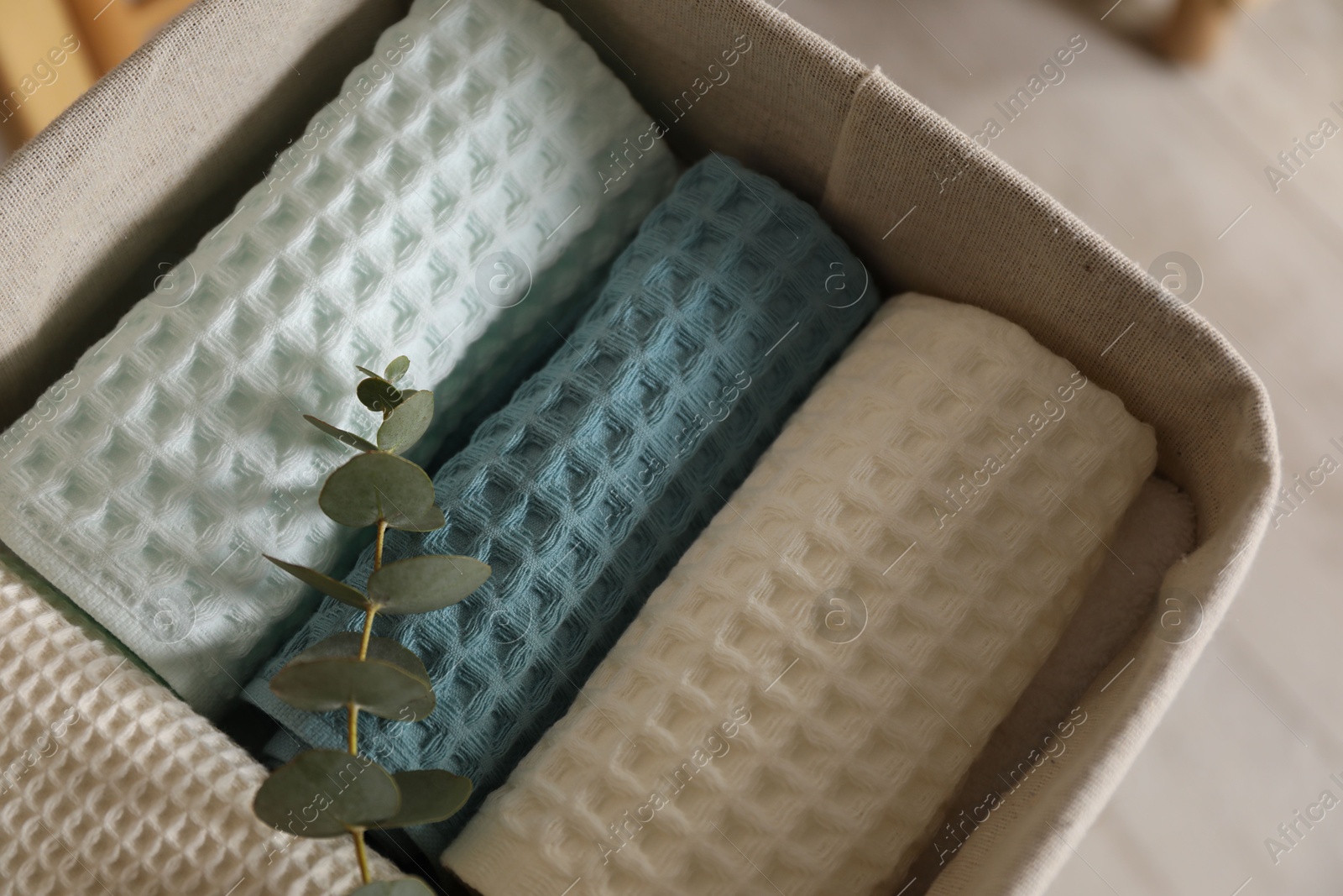 Clean waffle towels and branch in basket indoors, closeup Photo of Clean waffle towels and branch in basket indoors, closeup