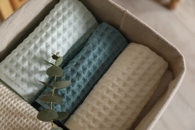 Photo of Clean waffle towels and branch in basket indoors, closeup