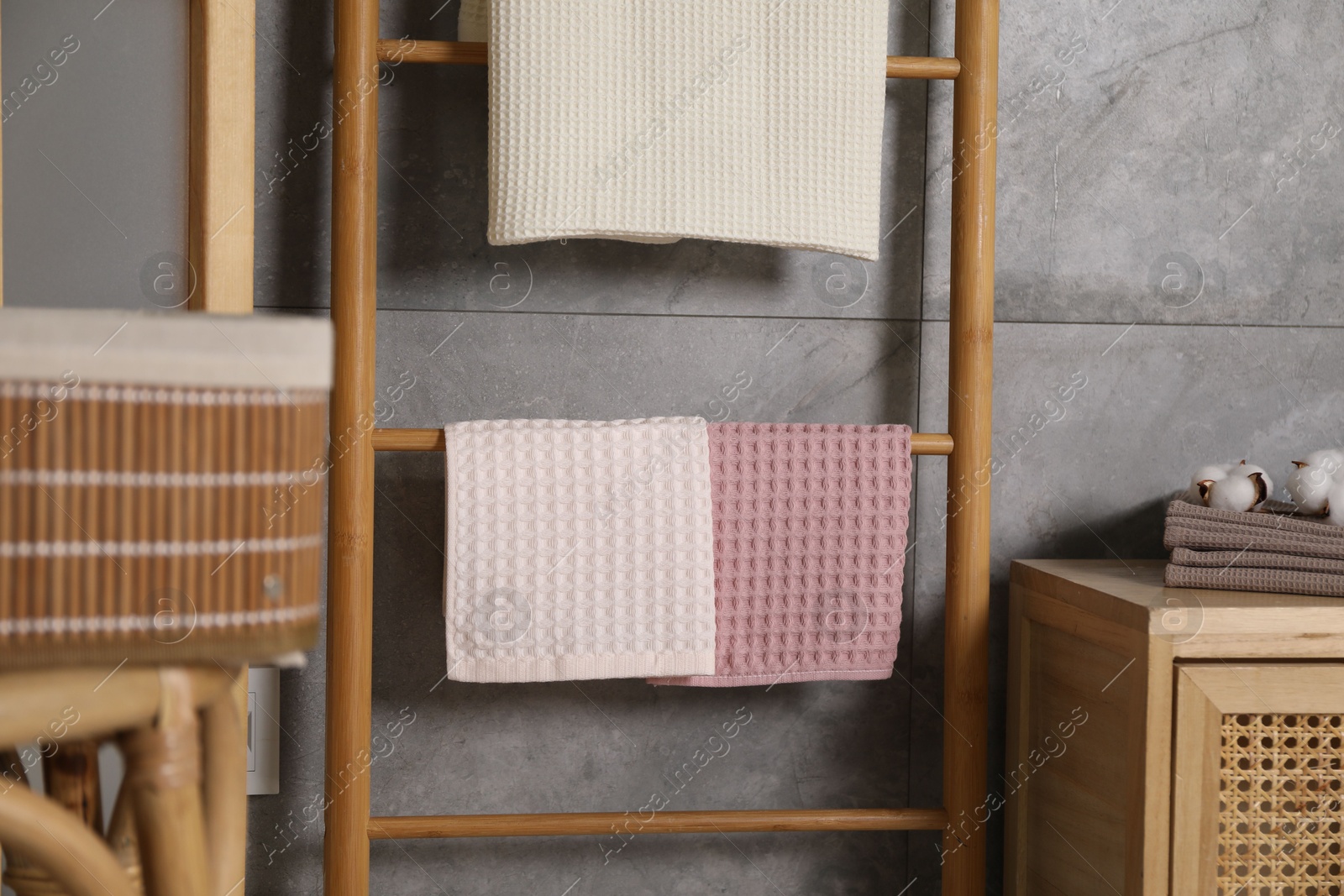 Clean waffle towels, wooden rack and dresser near grey wall in bathroom Photo of Clean waffle towels, wooden rack and dresser near grey wall in bathroom