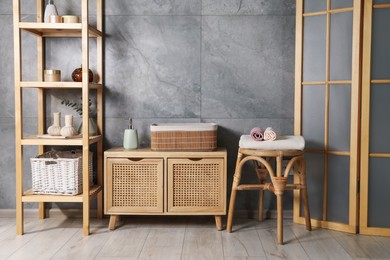 Photo of Clean waffle towels, wooden rack and dresser near grey wall in bathroom