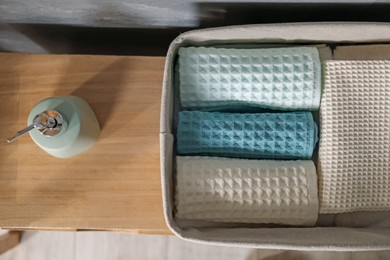 Photo of Clean waffle towels and reed diffuser on wooden dresser in bathroom, flat lay