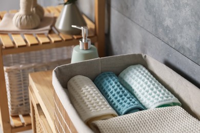 Photo of Clean waffle towels on wooden dresser in bathroom, closeup