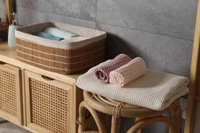 Photo of Clean waffle towels on chair and dresser in bathroom, closeup