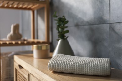 Photo of Clean waffle towel on wooden dresser in bathroom, closeup