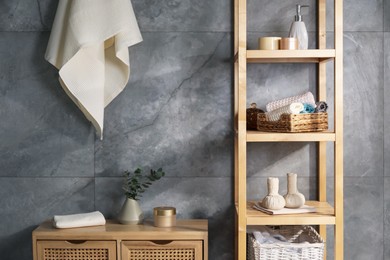 Photo of Clean waffle towels and other bath products near grey wall in bathroom