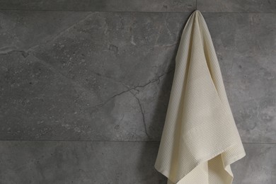 Photo of Clean waffle towel hanging on grey wall, space for text