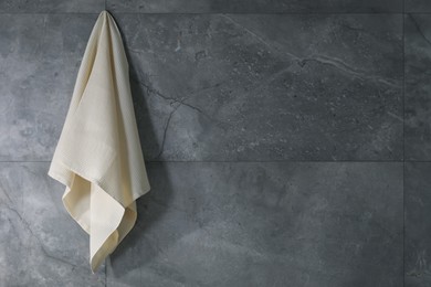 Photo of Clean waffle towel hanging on grey wall, space for text