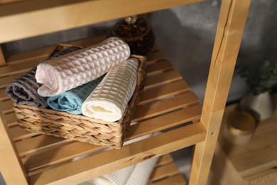 Photo of Clean waffle towels on wooden shelving unit near grey wall in bathroom, closeup