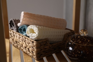 Photo of Clean waffle towels on wooden shelving unit near grey wall in bathroom, closeup
